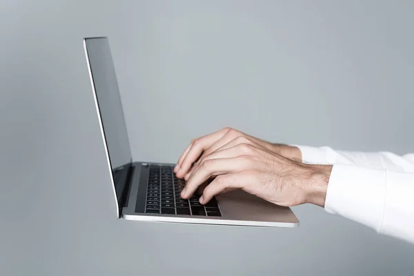 Vista recortada del hombre usando el ordenador portátil aislado en gris - foto de stock