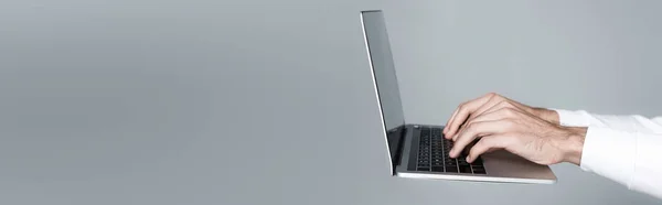 Ausgeschnittene Ansicht des Menschen mit Laptop in der Luft isoliert auf grau, Banner — Stockfoto