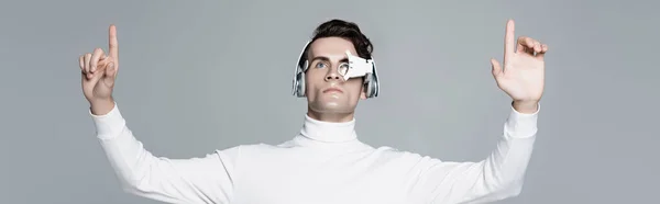 Cyborg in headphones and digital eye lens using something isolated on grey, banner — Stock Photo