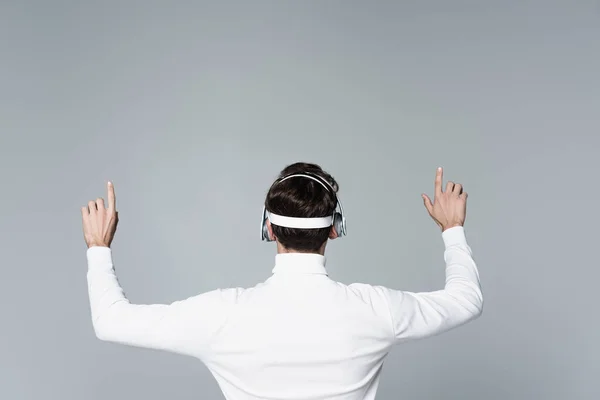 Back view of cyborg in headphones using something isolated on grey — Stock Photo