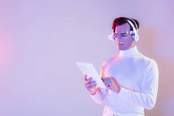 Cyborg in headphones and eye lens using digital tablet on purple background — Stock Photo