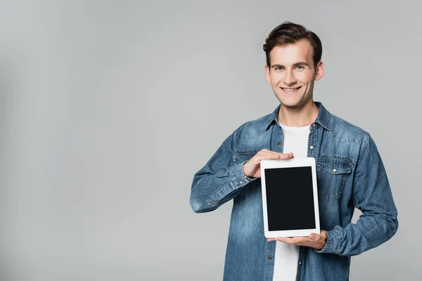 Homme positif montrant tablette numérique avec écran blanc isolé sur gris — Photo de stock