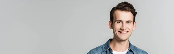 Young man smiling at camera isolated on grey, banner — Stock Photo