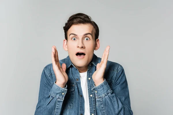 Homme choqué en veste en denim regardant la caméra isolée sur gris — Photo de stock