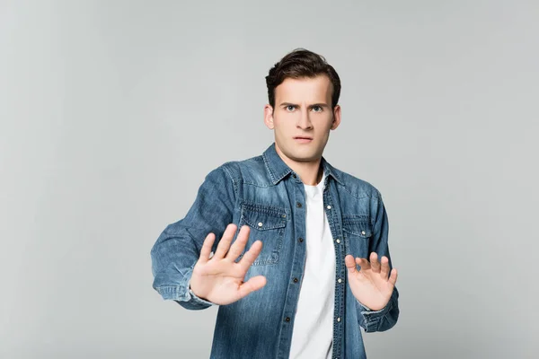 Scared man showing stop gesture isolated on grey — Stock Photo