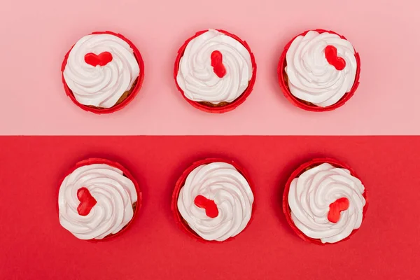 Vista superior de cupcakes de San Valentín sobre fondo rosa y rojo - foto de stock