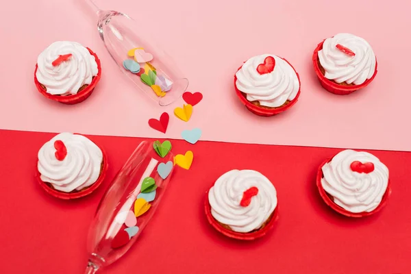 Vista superior de valentines cupcakes e taças de champanhe com corações em fundo rosa e vermelho — Fotografia de Stock