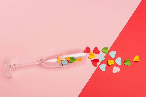 Draufsicht auf Sektglas mit Herzen auf rosa und rotem Hintergrund — Stockfoto