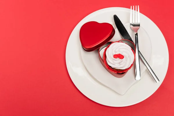 Top view of cupcake on plate with cutlery on red background — Stock Photo