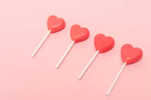 Heart shaped lollipops on pink background — Stock Photo
