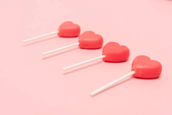 Heart shaped lollipops on pink background — Stock Photo