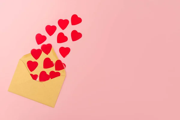 Draufsicht auf rote Herzen und Umschlag auf rosa Hintergrund — Stockfoto