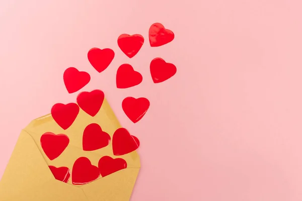 Top view of red hearts and envelope on pink background — Stock Photo