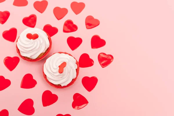 Vista superior de corações vermelhos e cupcakes em rosa — Fotografia de Stock