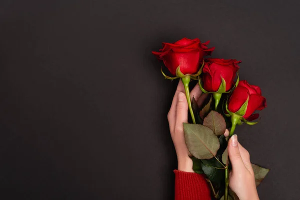 Vista cortada de mulher segurando rosas vermelhas isoladas em preto — Fotografia de Stock