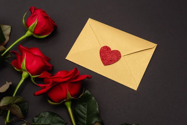 Top view of roses and valentines envelope isolated on black — Stock Photo