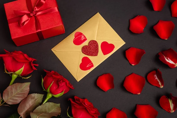 Vista superior de rosas, presente dos namorados e envelope isolado em preto — Fotografia de Stock