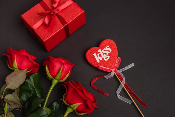 Top view of roses, valentines gift and heart on stick isolated on black — Stock Photo