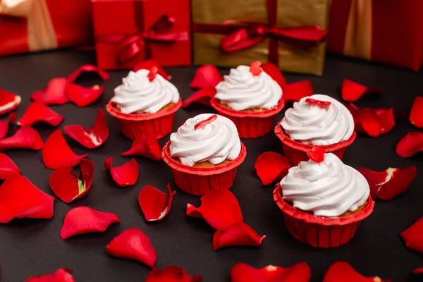 Pétalas de rosa e cupcakes valentines isolados em preto — Fotografia de Stock