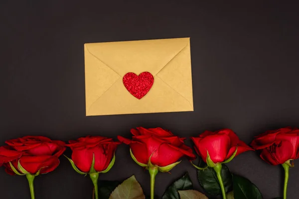 Top view of roses and envelope isolated on black — Stock Photo