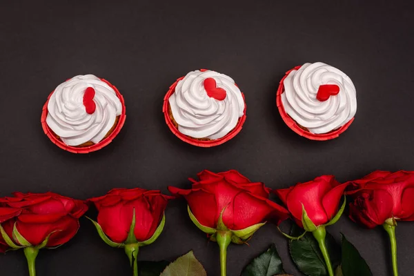 Vista dall'alto di rose e cupcake isolati su nero — Foto stock