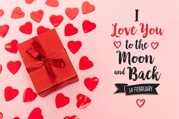 Vista dall'alto di cuori di carta rossa e scatola regalo vicino ti amo alla luna e ritorno, 14 febbraio lettering su sfondo rosa — Foto stock