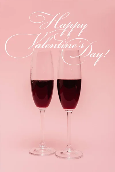 Красное вино в бокалах возле счастливого дня святого Валентина с надписью на розовом — стоковое фото