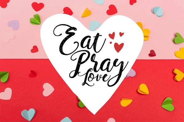 Top view of colorful paper hearts near eat pray love lettering on red and pink — Stock Photo