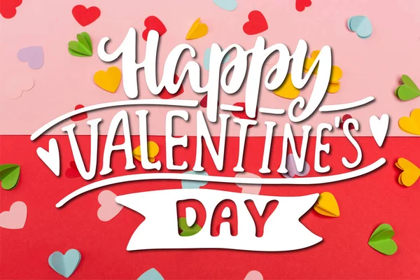 Vue du haut des coeurs de papier colorés près de joyeux lettrage Saint-Valentin sur rouge et rose — Photo de stock