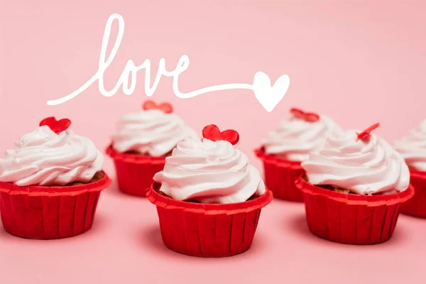 Cupcake di San Valentino con cuori rossi vicino all'amore lettering su sfondo rosa — Foto stock