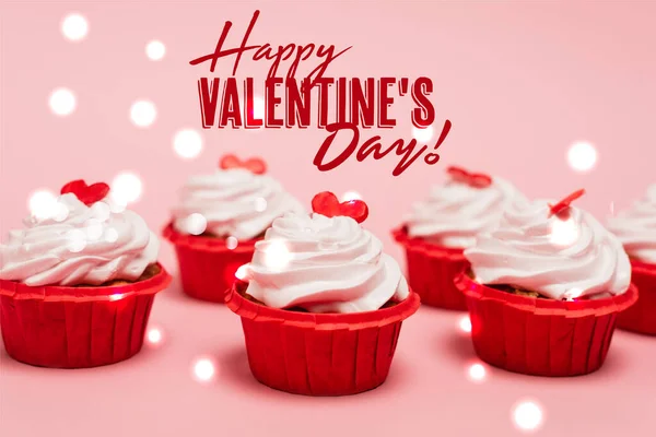 Leckere Cupcakes mit roten Herzen in der Nähe glücklich Valentinstag Schriftzug auf rosa Hintergrund — Stockfoto