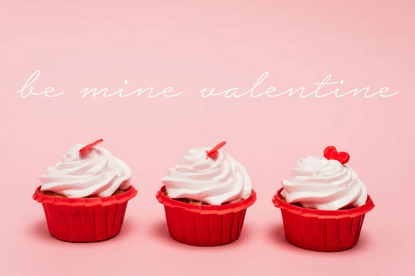 Cupcakes de San Valentín con corazones rojos cerca de ser mío letras de San Valentín sobre fondo rosa - foto de stock