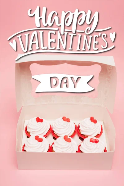 Schachtel mit leckeren Cupcakes in der Nähe von glücklichen Valentinstag Schriftzug auf rosa Hintergrund — Stockfoto