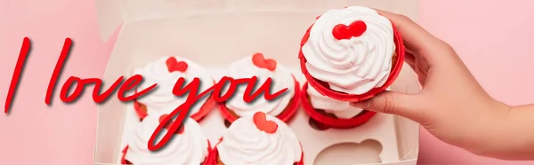 Corte vista de mulher segurando valentines cupcake perto da caixa e eu amo você lettering no fundo rosa, banner — Fotografia de Stock