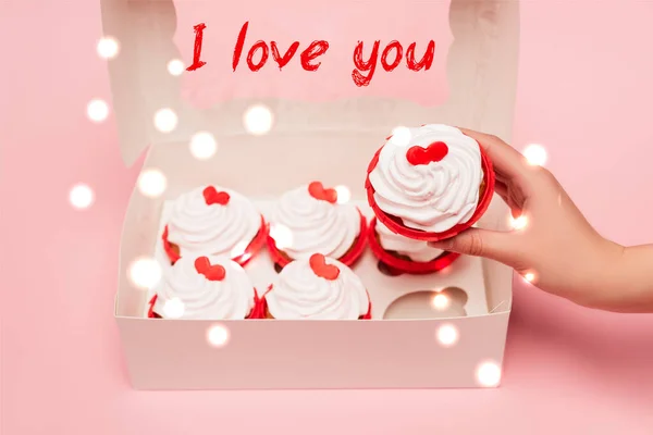 Vue recadrée de femme tenant des valentines cupcake près de la boîte et je vous aime lettrage sur fond rose — Photo de stock