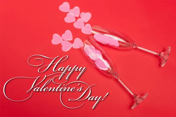 Top view of pink hearts in champagne glasses near happy valentines day lettering on red background — Stock Photo