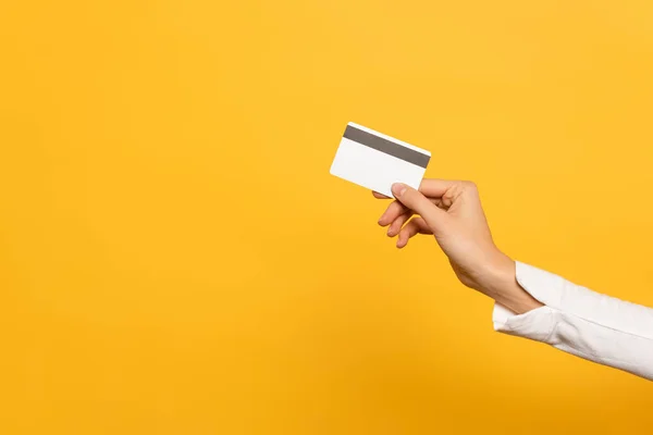 Обрізаний вид жіночої руки з кредитною карткою ізольовано на жовтому — стокове фото