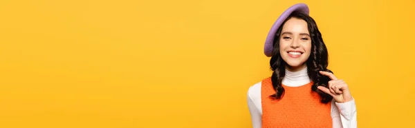 Positive brunette woman in beret showing small amount gesture while looking at camera isolated on yellow, banner — Stock Photo