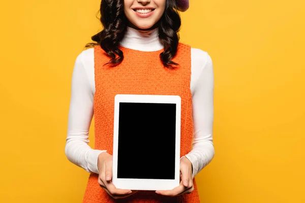 Vista recortada de mujer morena rizada mostrando tableta digital con pantalla en blanco aislada en amarillo - foto de stock