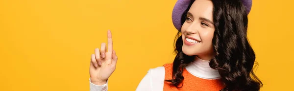 Happy brunette woman in beret with idea gesture looking away isolated on yellow, banner — Stock Photo