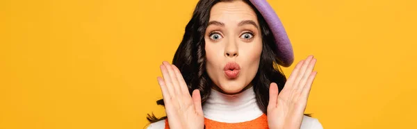 Surprised brunette woman in beret showing palms while looking at camera isolated on yellow, banner — Stock Photo