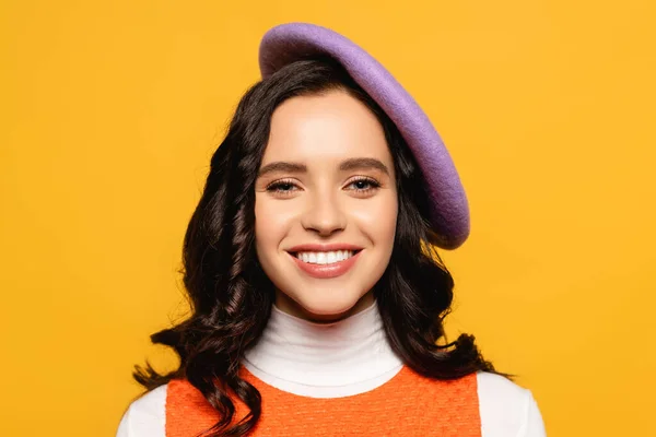 Portrait de femme brune souriante en béret regardant la caméra isolée sur jaune — Photo de stock