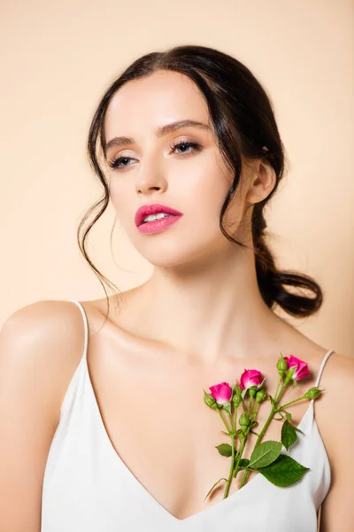 Sensual young woman looking away near flowers isolated on pink — Stock Photo