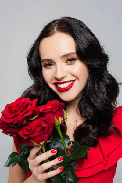 Feliz joven mujer sosteniendo ramo de rosas aisladas en gris - foto de stock
