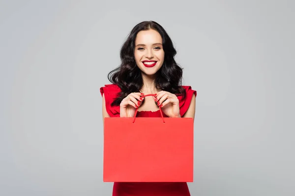 Happy young woman holding shopping bag isolated on grey — Stock Photo
