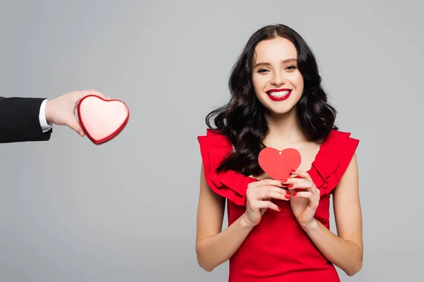 Man holding heart-shaped box near happy woman with paper heart isolated on grey — Stock Photo