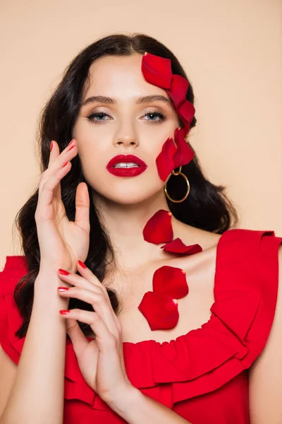 Brunette jeune femme avec des pétales de rose rouge sur le visage isolé sur rose — Photo de stock