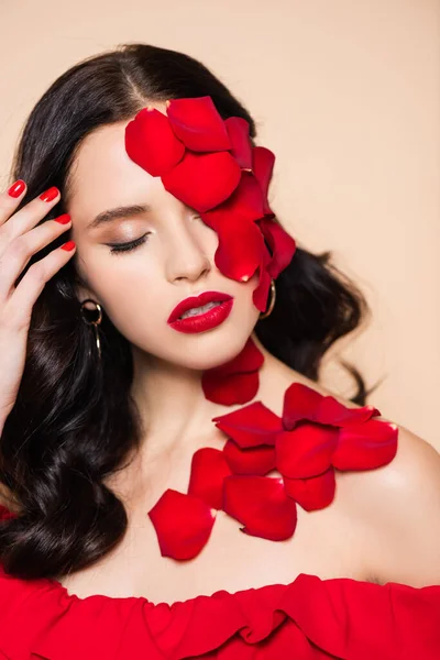 Pretty young woman with closed eyes and petals of red rose on face isolated on pink — Stock Photo