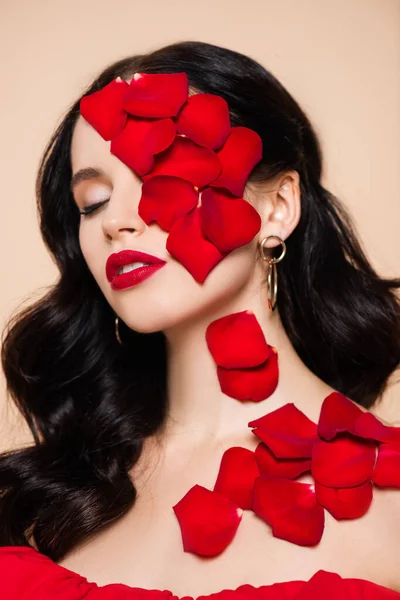 Молода жінка з закритими очима і пелюстками троянд на обличчі ізольована на рожевому — стокове фото