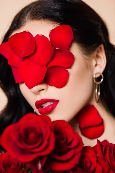 Молода брюнетка з пелюстками на обличчі та червоними трояндами — стокове фото